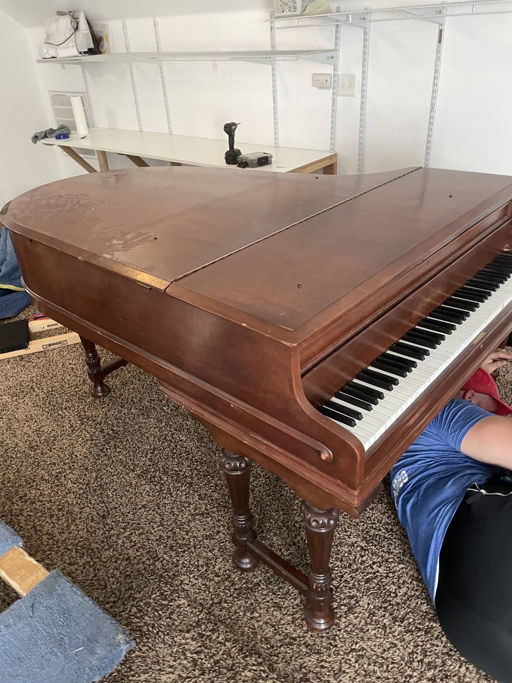 A wooden grand piano with the keyboard open, prepared for a professional piano move
