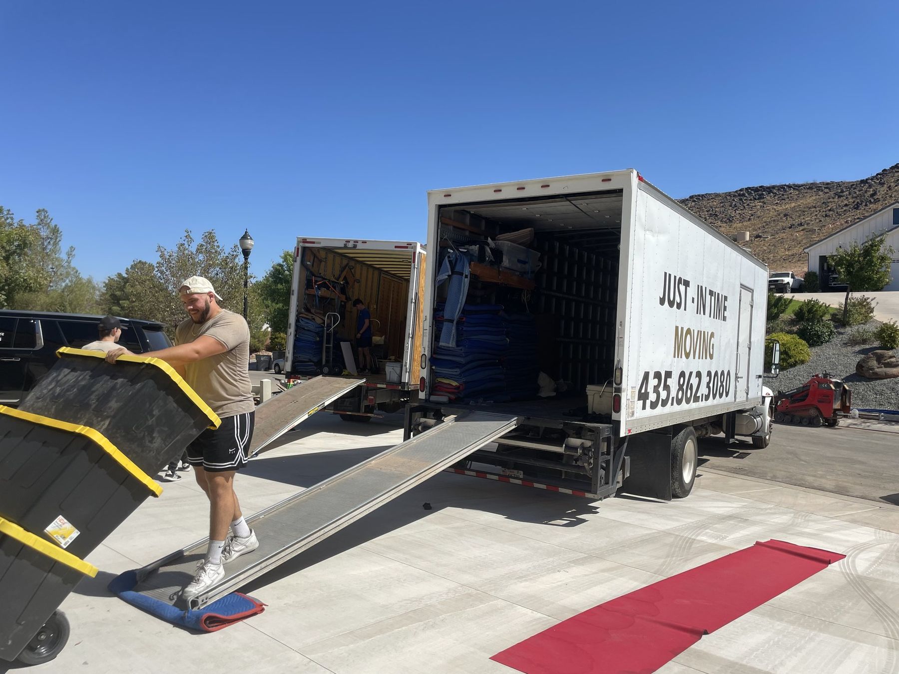 A mover wheeling a loaded dolly up the ramp into a Just-In Time moving truck