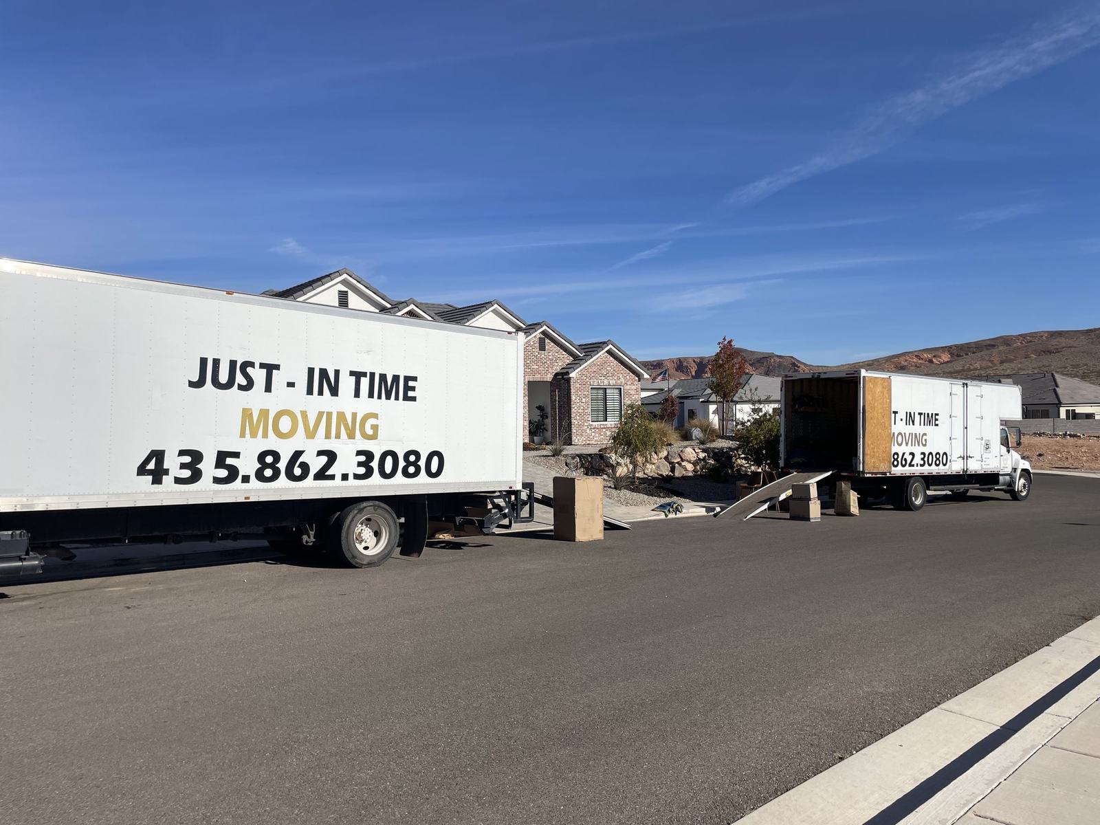 A Just-In Time moving truck parked on a residential street with Southern Utah hills in the background