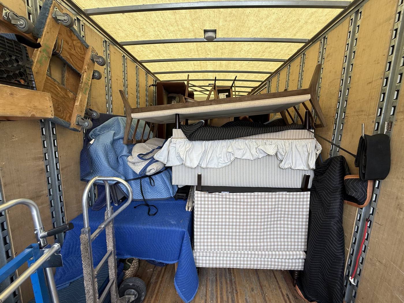 Hand trucks, dollies and a wrapped mattress loaded inside a Just-In Time moving truck