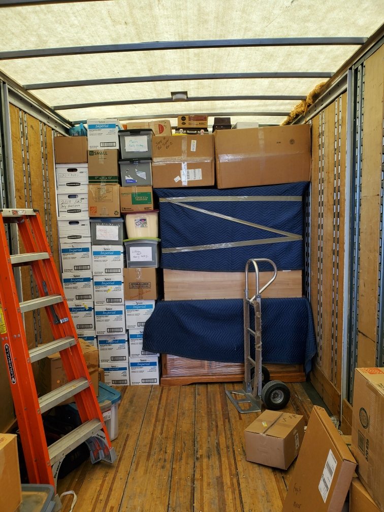 A moving truck packed wall to wall with cartons, a step ladder and a hand truck