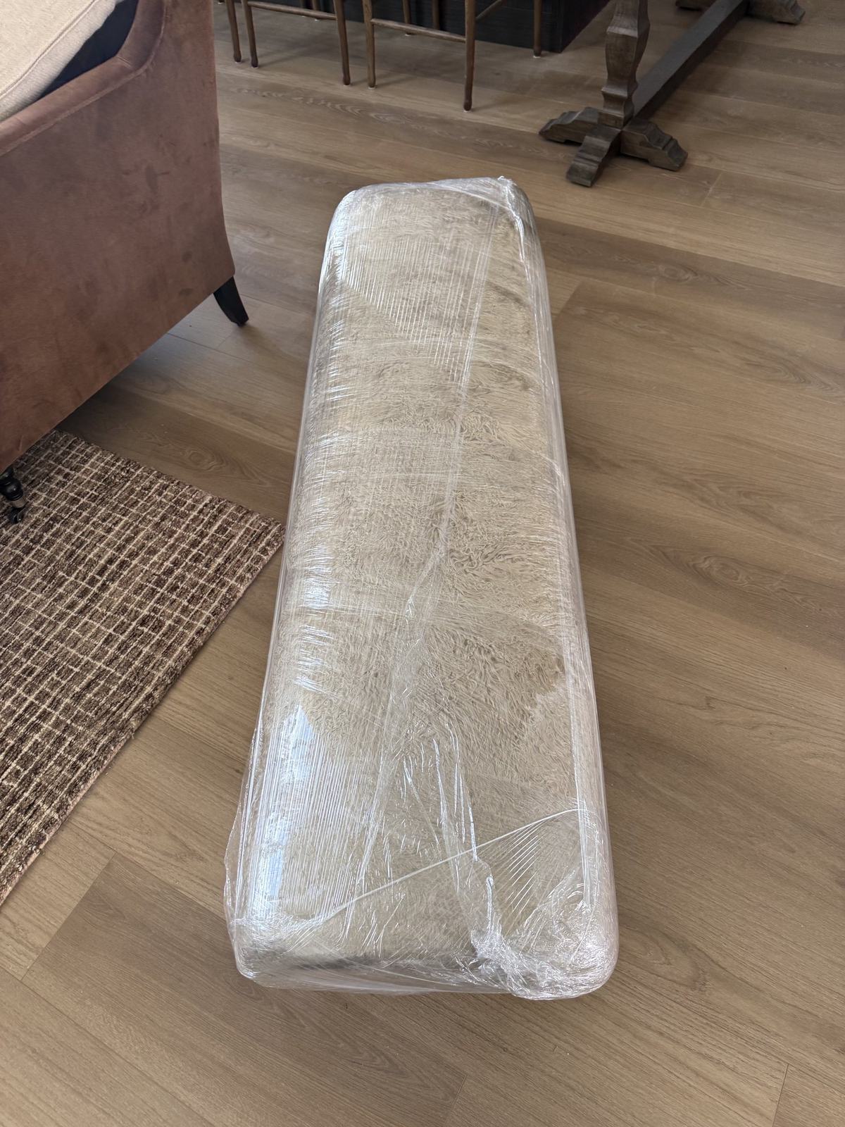 A mattress fully shrink-wrapped in protective plastic, ready to be carried out